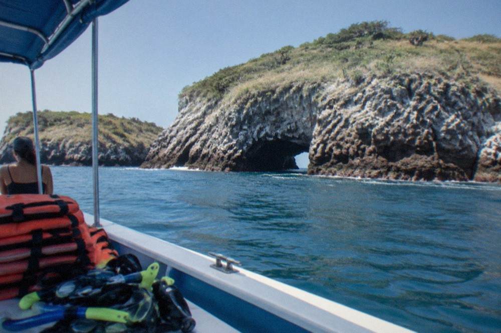 Snorkel boat anchored near rocky islands offshore with calm blue water