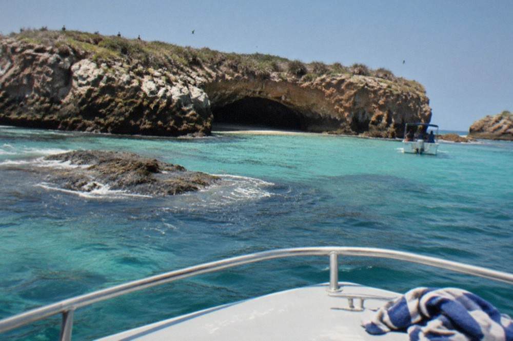 Clear turquoise water and rocky shoreline seen from a tour boat approaching a protected island