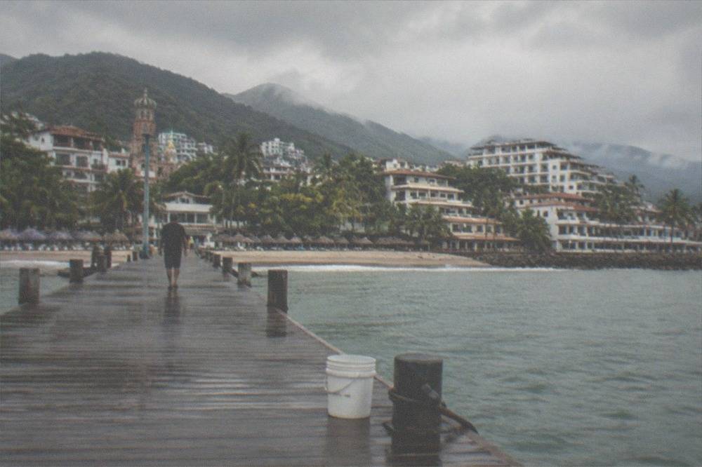 Wooden pier extending into calm bay water with hills in the background
