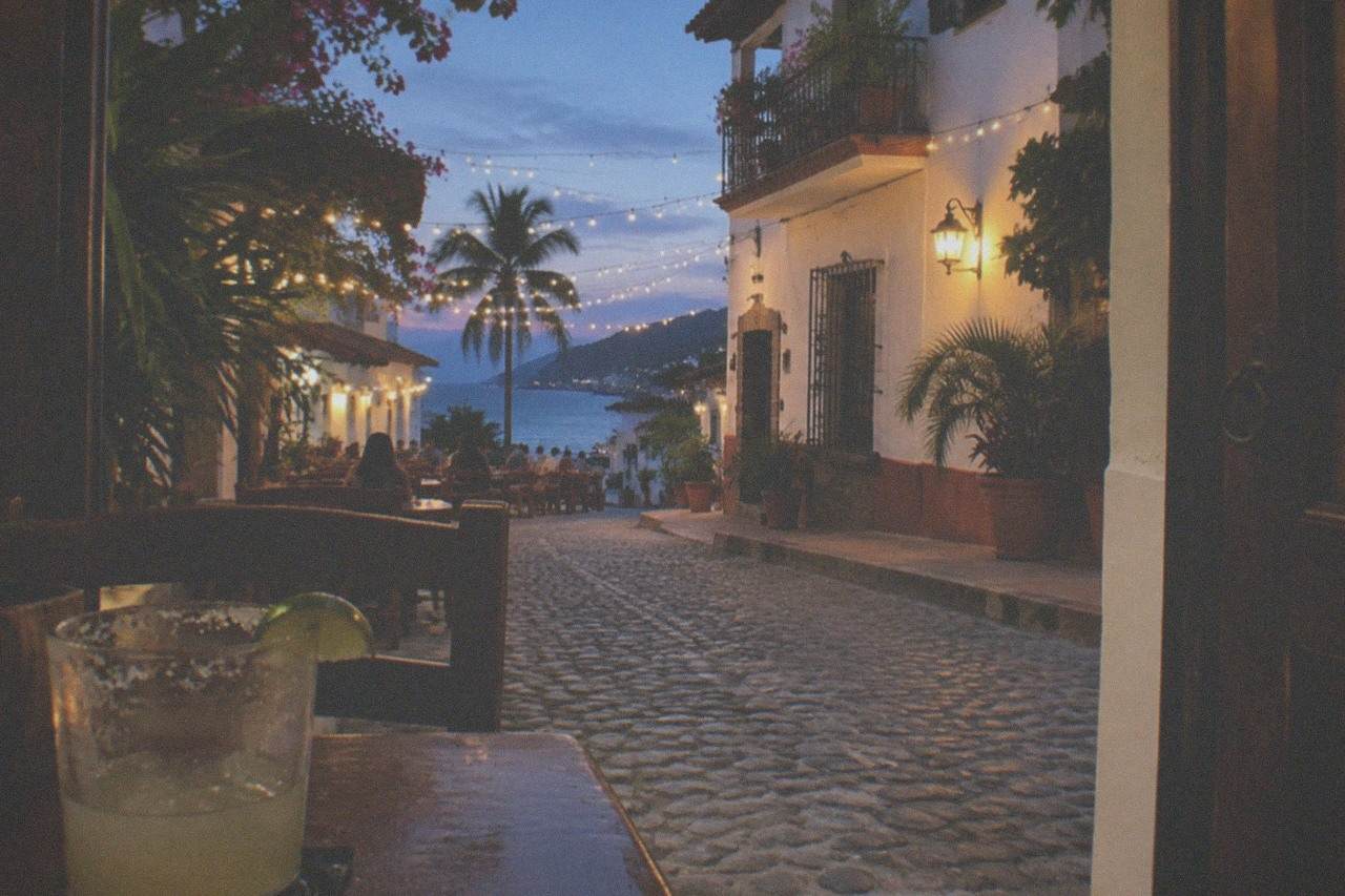 Outdoor restaurant tables with string lights on a cobblestone street in Puerto Vallarta at dusk