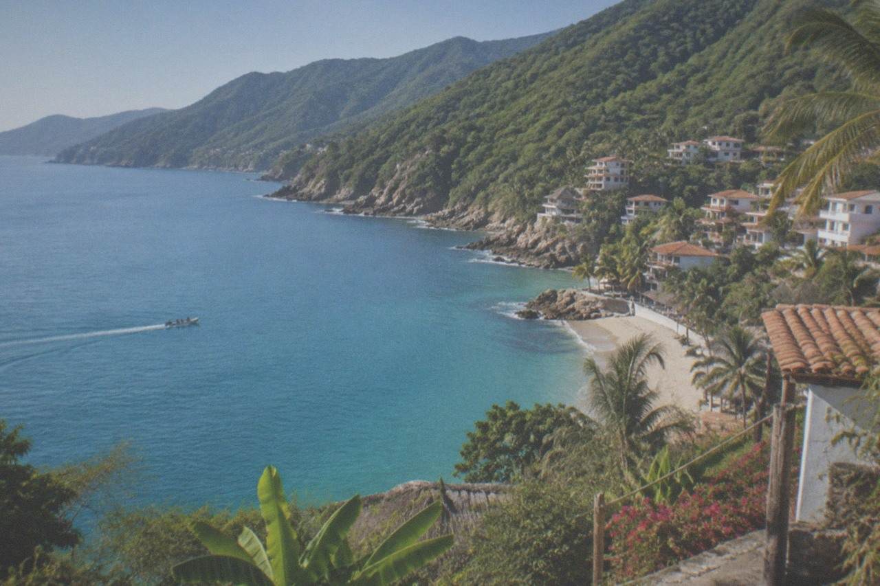 Calm turquoise bay water meeting green jungle covered mountains along a Pacific coastline