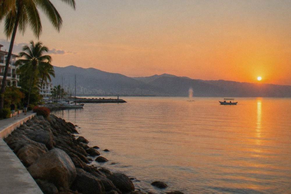 Flat calm ocean surface in Banderas Bay at sunrise with a whale spout visible in the distance