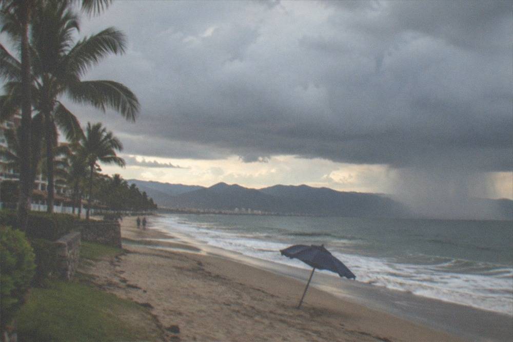 Dark rain clouds gathering over the ocean horizon near a coastal town