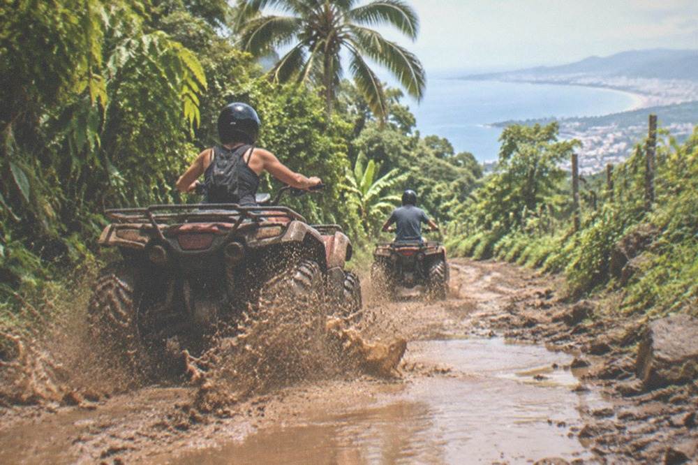 ATV vehicles on a dirt jungle trail with green trees on both sides