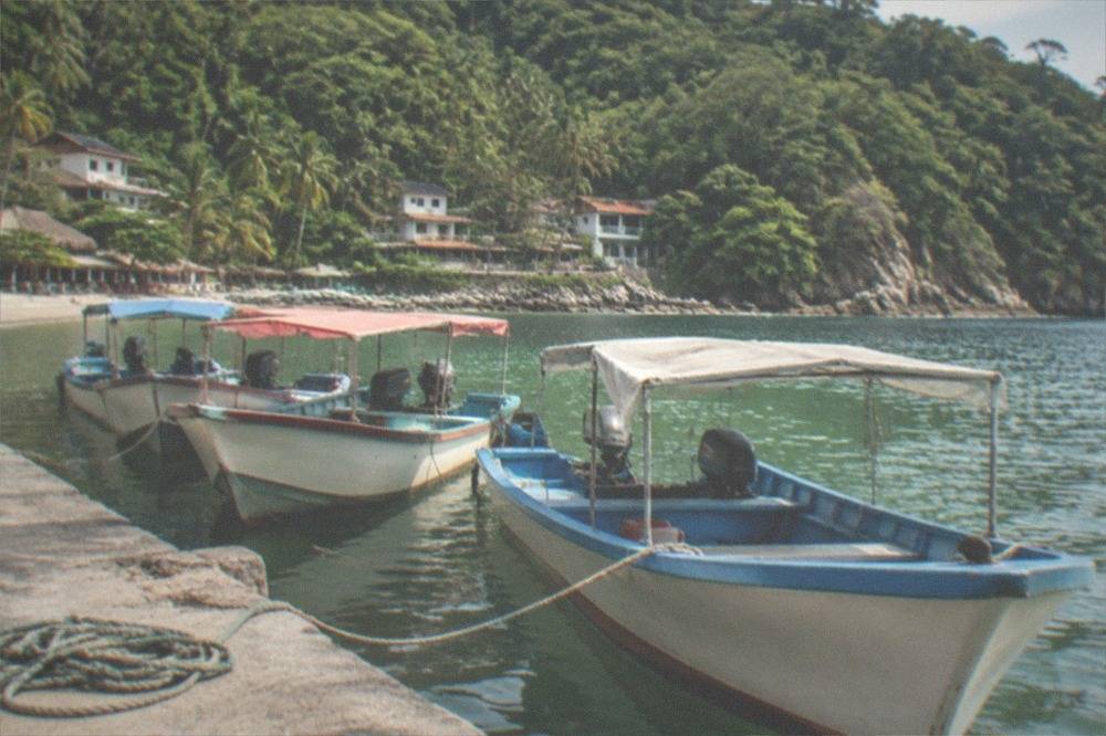 Wooden water taxi boats moored at a small beach cove with jungle hills behind