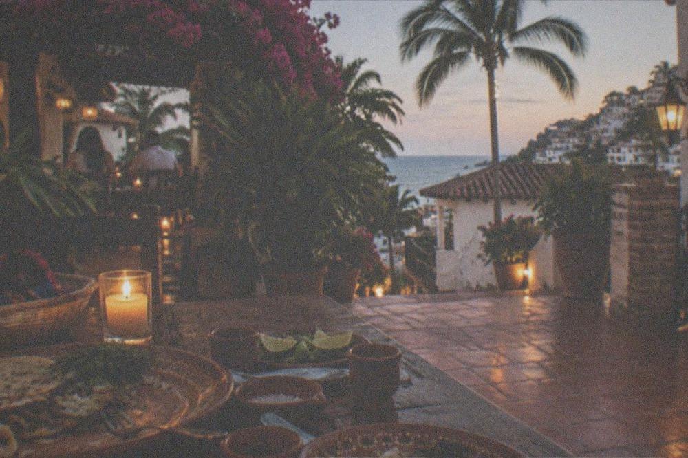 Evening table set with tequila glasses, lime and salt beside plates of Mexican food
