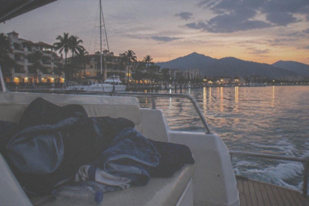 A wooden boat deck at dusk with a folded towel and light jacket on a bench seat