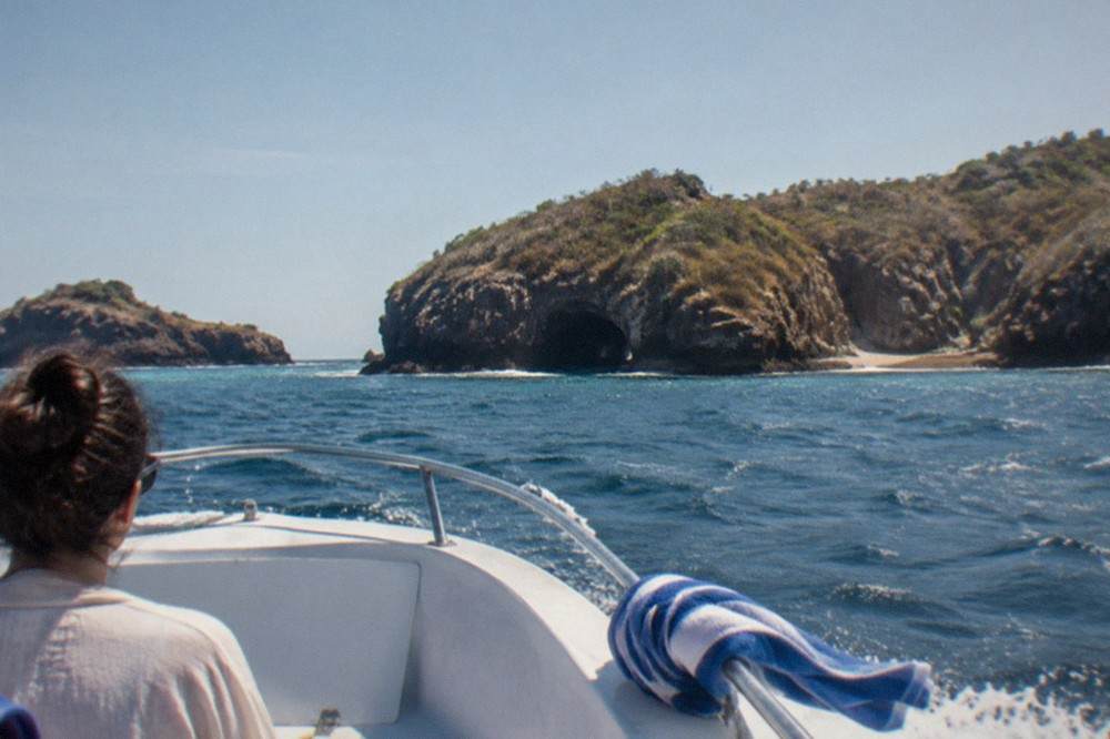 Speedboat crossing open water toward a rocky island coastline in Banderas Bay