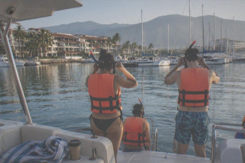 Group of snorkelers in life jackets preparing to enter the water from a boat deck