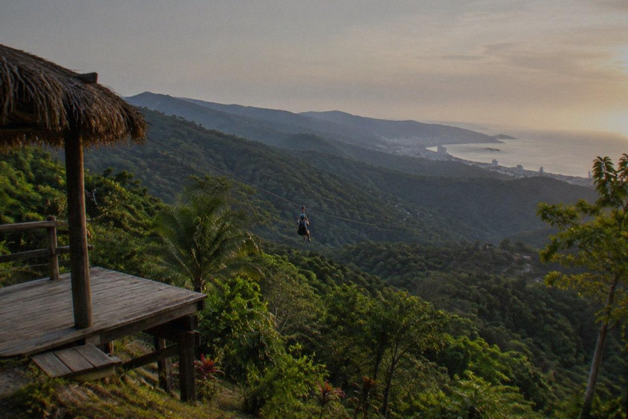 A rider in a helmet glides along a cable above the treetops in the Sierra Madre foothills of Jalisco.